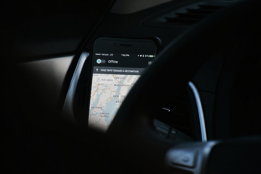 Smartphone mounted on a car dashboard displaying the Uber driver app set to offline over a map