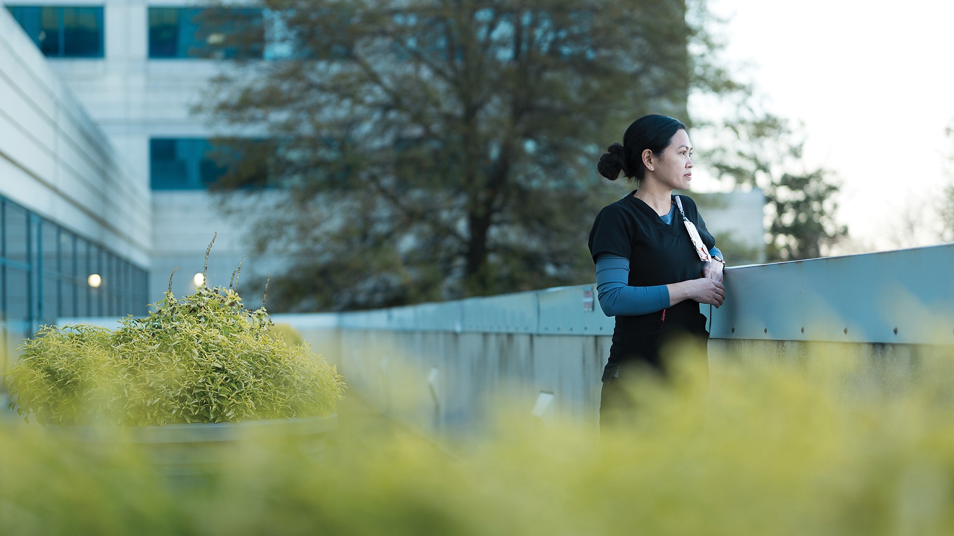 Clinician standing on an outdoor walkway outside a hospital building
