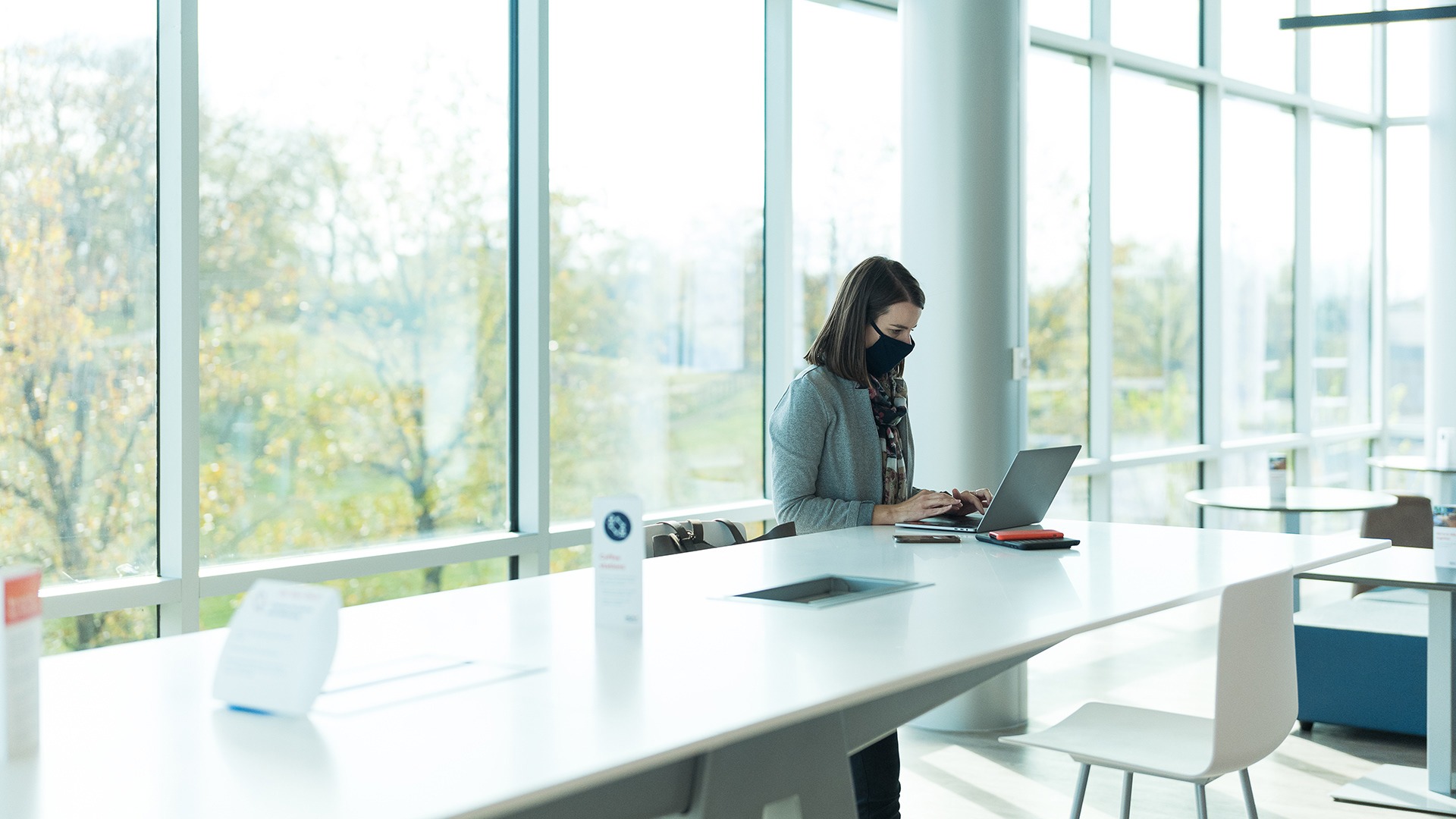 Employee working at a laptop in a bright, glass-walled office space