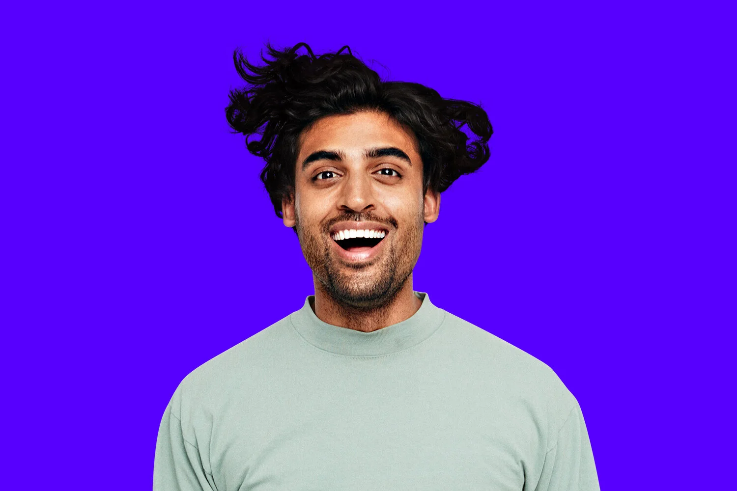 Portrait of a laughing man with windswept hair against a bright SmileDirectClub-purple background